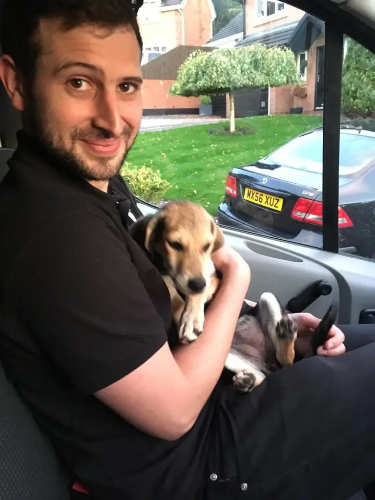 smiling man with puppy on his lap